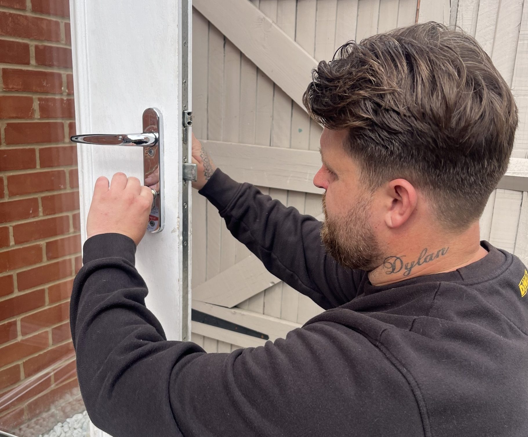 Connor from Seymour Locksmiths adjusting a door lock on a white external door